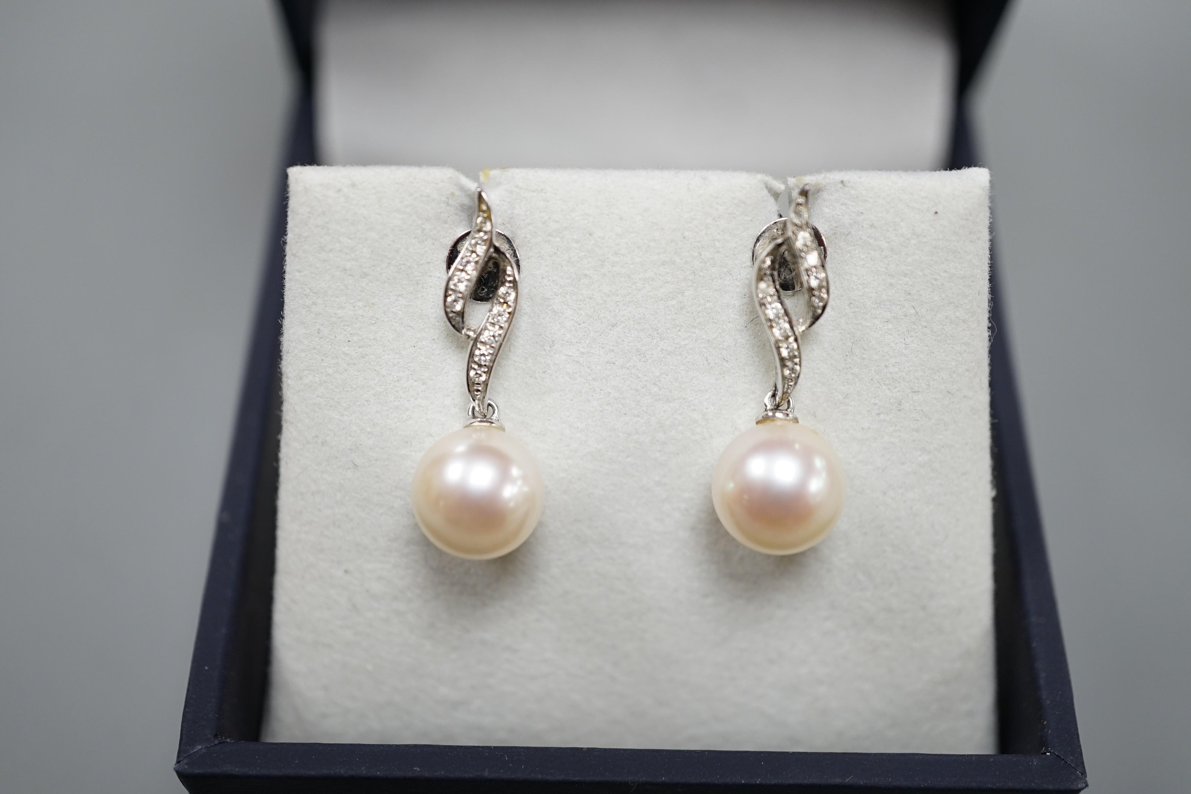 A modern pair of 14k white metal, cultured pearl and diamond set drop earrings, 24mm, gross weight 3.8 grams.